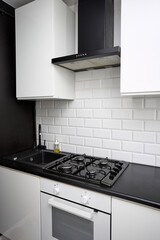 Small  kitchen design with white kitchen cabinets, white kitchen island with lots of storage, black countertops, subway tiles, gas stove.