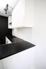 Small  kitchen design with white kitchen cabinets, white kitchen island with lots of storage, black countertops, subway tiles, gas stove