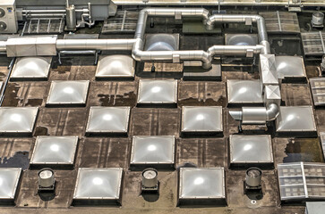 Piper and other air conditioning machinery on a roof with a repetitive pattern of skylights
