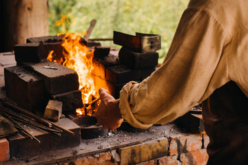 Fototapeta A blacksmith hardens steel at high temperature in a homemade furnace in the village obraz