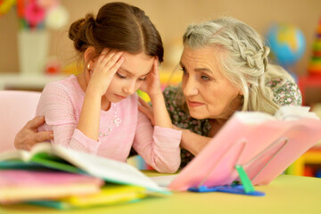 Obraz na płótnie Canvas Grandmother with cute little girl doing homework