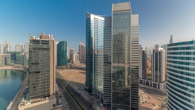 Cityscape of glass skyscrapers with sun reflections of Dubai Business Bay during sunrise with water canal aerial timelapse. Modern skyline with towers and waterfront. A center of international
