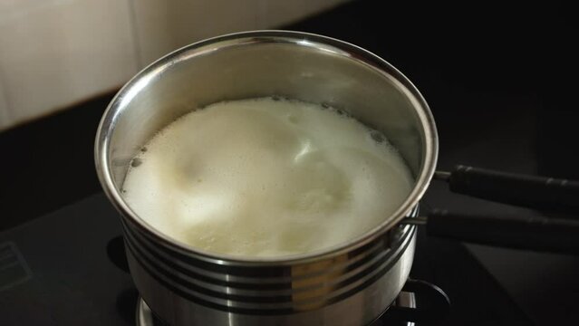 Boiling milk on gas stove, White thick layer of form over milk. Separate thick cream from milk. Curdled milk. Homogenized milk. Indian malai from milk.	