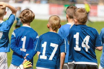 Football players wearing blue jersey shirts in the youth team. Boys in blue jersey shirts watching a tournament game. Group of kids in a school sports team