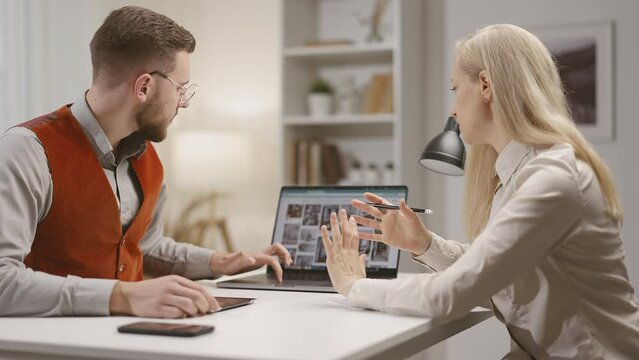 Caucasian male and female designers discussing visual progect in the office, collaboartion