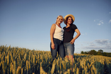 Two women standing on the agriculture field with growing wheat