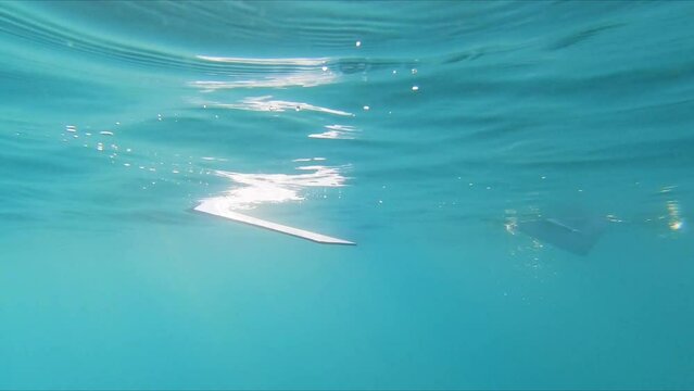 Underwater lurking point of view watching rowing oars paddling through water