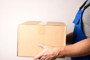 Delivery man holding cardoard box on white background with copy space, close-up