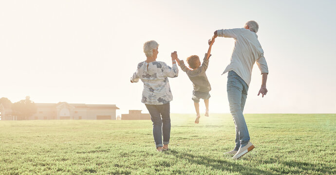 Love, grandparents and child being playful, happy and bonding on grass, outdoor and together. Grandmother, grandfather and kid enjoy summer holidays, adventure or travel for walking or holding hands