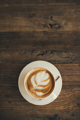 White cup with fresh cappuccino on wooden background
