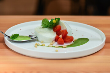Caprese salad on a white plate. Arugula, walnut, tomato, mozzarella, oil. Italian salad