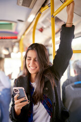 Young woman commuting on the bus and looking at her cell phone - 541207188