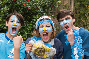 Familia con la cara pintada con los colores de la bandera Argentina, felices alentando al...
