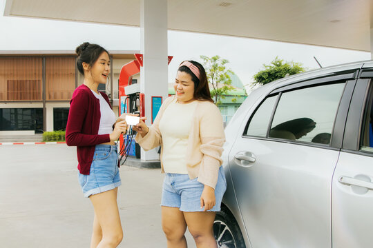 Convenience beautiful asian woman who is a gas card premium member modern gas station collecting points with her chubby female friends expressing their appreciation for their trendy girlfriends.