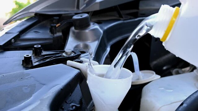 closeup of pouring deionized water into car tank for windshield wipers