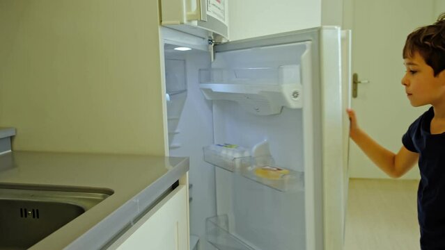 little boy opens the refrigerator and takes an apple, a hungry child