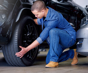 Man, car mechanic and tire change in garage, vehicle maintenance or service. Expert, professional...