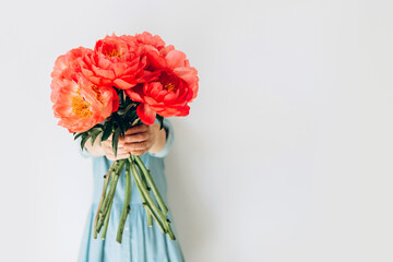 Photo of hipster dreamy girl embracing a huge bouquet of peonies closed isolated turquoise color background