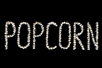 the word popcorn on a black background. The word popcorn laid out from popcorn