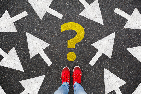 woman in red sneakers standing on asphalt next to multitude of arrows in different directions and question mark, confusion choice chaos concept