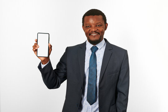 Smiling african american black man in business suit with smartphone blank mockup in hand, white wall background. Portrait of happy black businessman holding white phone mock up for advertising - Powered by Adobe
