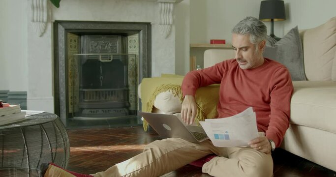 Mid Adult Male Looking at Home finances using a Laptop in Living room