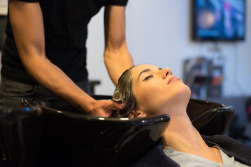 Hairdresser washing hair of the woman in modern hair salon - 541224140