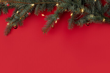 Christmas red background with fir tree branches and decor.