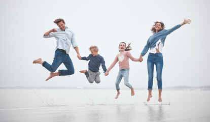 Family, funny and jumping on the beach together while on holiday. Happy family with children,...
