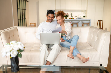 Two young people sitting on the sofa and choosing something online