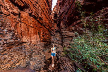 backpacker girl hiking in a very narrow canyon in karijini national park in western australia,...