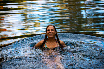 A beautiful girl in a bikini takes a refreshing dip in a rock pool under in karijini national park,...