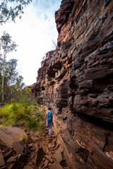 backpacker girl hiking through a canyon in karijini national park in western australia, hiking in...