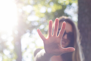 Smiling woman showing her palm or 5 fingers gesture. Selective focus, blurred.