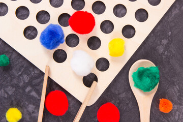 Colorful pompoms using for playing and development of kids motor skills, coordination and logical thinking