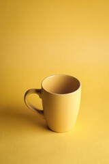 Close up of yellow coffee mug on yellow background