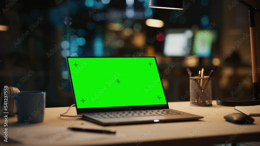 Fototapete laptop standing on a desk with a green screen chromakey mock up display. table with computer, coffee