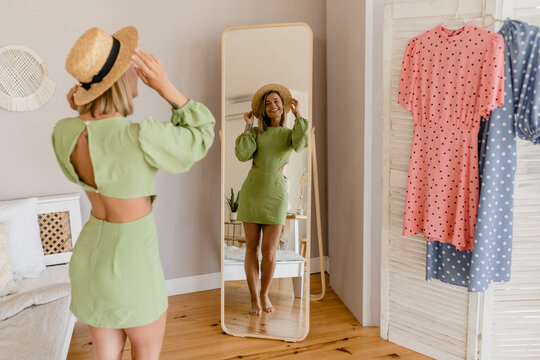 young pretty woman in green dress trying on style trend dress looking in mirror