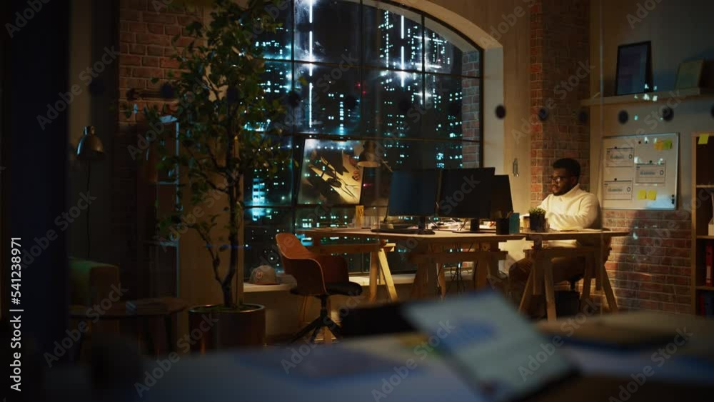 Aufkleber Focused Project Manager Sitting at a Desk, Working Alone on a Computer in an Office at Night. African Marketing Specialist Researching a Project, Developing a Software Interface.