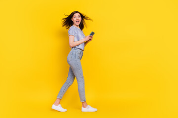 Full size photo of funky satisfied lady addicted user arm hold telephone device gadget go empty space isolated on yellow color background