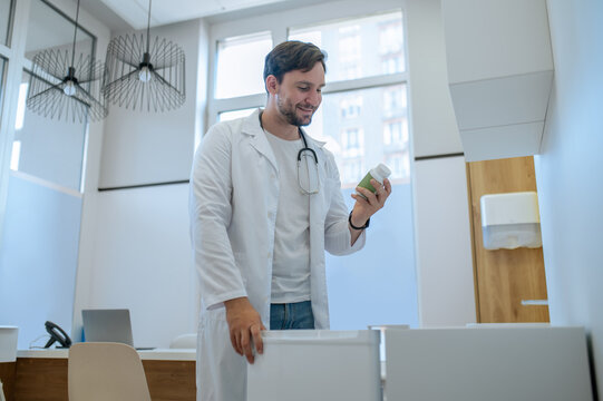 Smiling physician reading the label on the dietary supplement