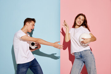Portrait of young man and woman, sport fans posing with football ball isolated over blue-pink...