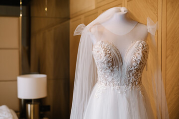 Fototapeta na wymiar The bride's dress in the hotel room on a mannequin. Details of the bride's dress. Lace dress. Wedding lace dress of the bride. 