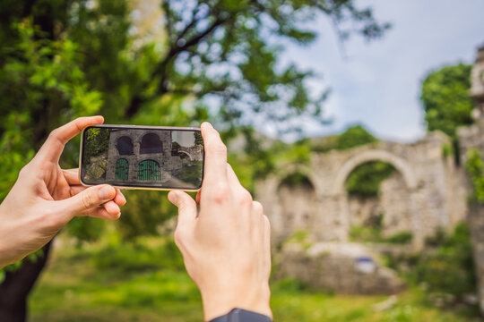 Augmented reality concept. Hand holding smart phone use AR application to check relevant information about building that was here in ancient times. Augmented reality in history and architecture