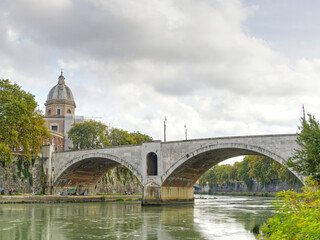 The Saint Angelo bridge spanning the Tiber river in Rome Italy as seen on a fall day.