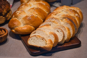 Delicious yeast bun on a wooden board. Tasty german yeast bun in slices with grated almonds. German traditional pastry called 'Hefezopf'. Freshly baked and sliced 'Zopf' from a German bakery. 