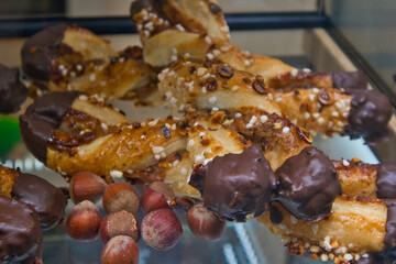 Sweet twisted puff pastry with crystal sugar and almonds. Chocolate-coated puff pastry with hazelnuts. Sweet pastry on a display in a bakery shop. Tasty baked sweet desert with almonds and chocolate. 