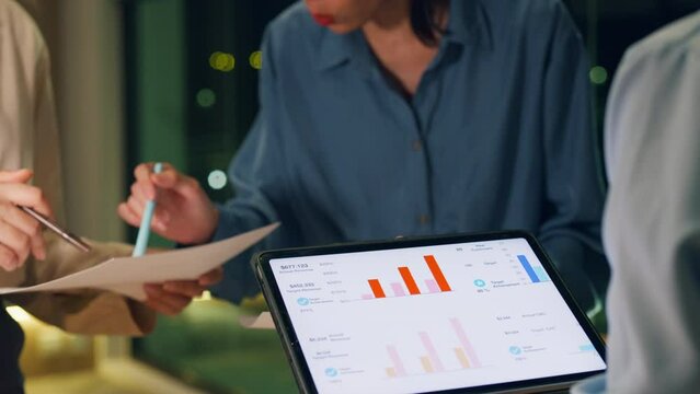 Close-up asia businesspeople meeting plan analysis statistics brainstorm and header of team hold tablet point graph chart and employee take note at home office night. Finance strategy success concept.