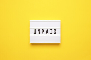 Lightbox with word unpaid on yellow background. Business and finance concept