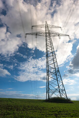 Electricity pylon for transmission and current transfer of high voltage through natural landscapes in front of cloudy sky